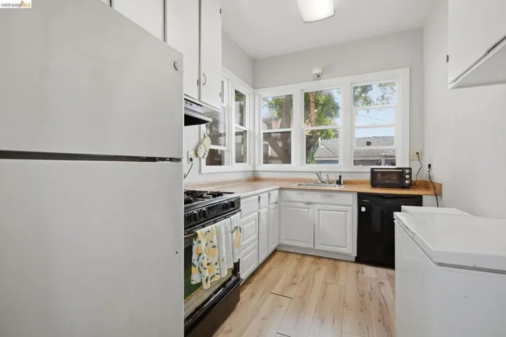 Kitchen featuring white cabinetry, wood-finish countertops, and wood-finish flooring
