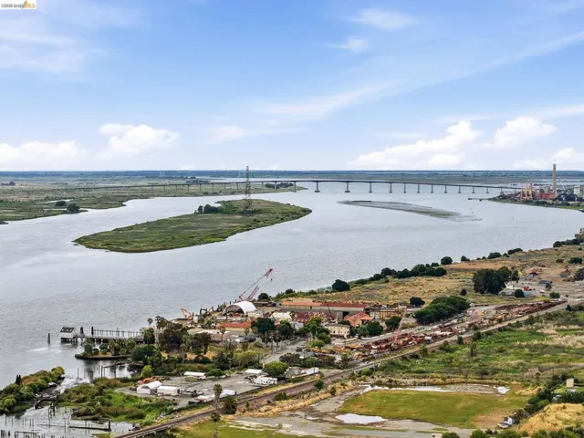 Expansive waterway with a distant bridge and a shoreline featuring a mix of developed and natural areas