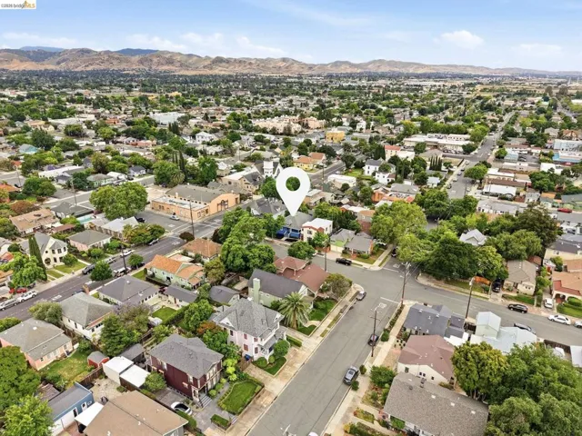 Residential area featuring a mix of mature trees and established homes, with distant hills visible