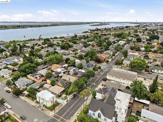 Aerial perspective showcasing a residential neighborhood with a large body of water, likely a river or bay, in the background