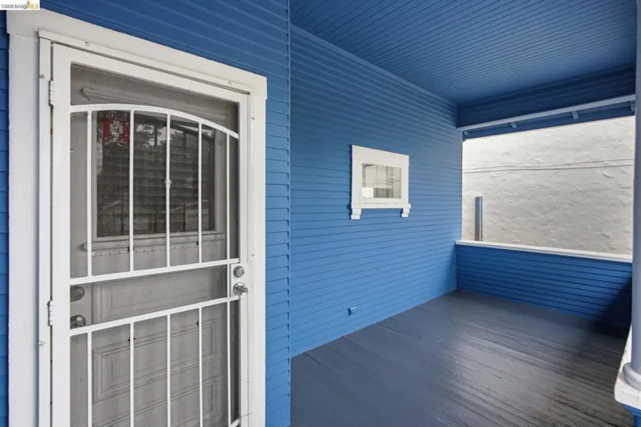 Covered porch featuring lap siding, beadboard ceiling, wood-finish flooring, a white security screen door, and a decorative small window