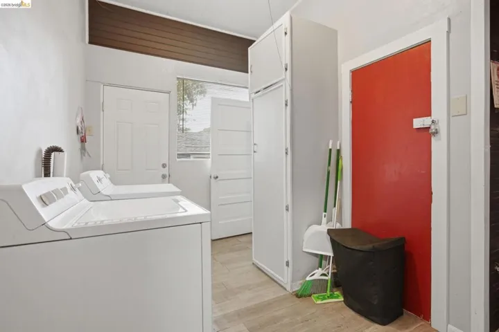 Utility room featuring light-toned flooring, white walls, and a wood-paneled ceiling accent
