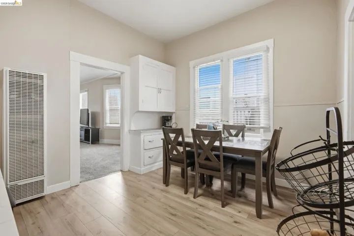 Dining area featuring wood-finish flooring, white built-in cabinetry with a countertop, and two large windows with blinds