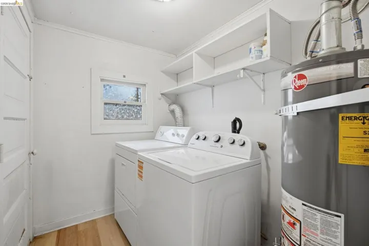 Dedicated utility area featuring wood-finish flooring, white walls, and a casement window with obscured glass