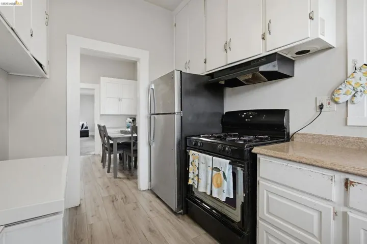 Kitchen featuring wood-finish flooring, white cabinetry, and a black gas range