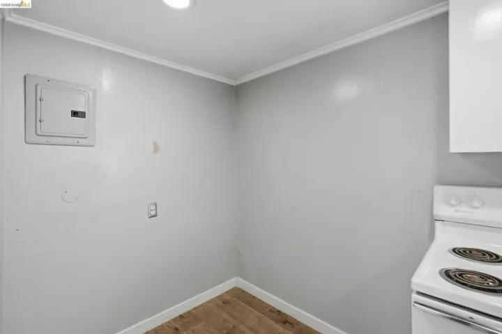 Wood-finish flooring with white baseboards, a wall-mounted electrical panel, and a recessed ceiling light