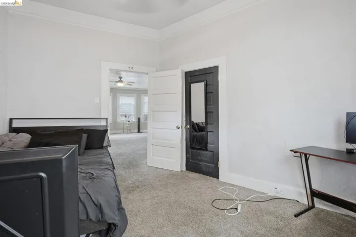 Carpeted room with white walls, crown molding, and a white paneled door