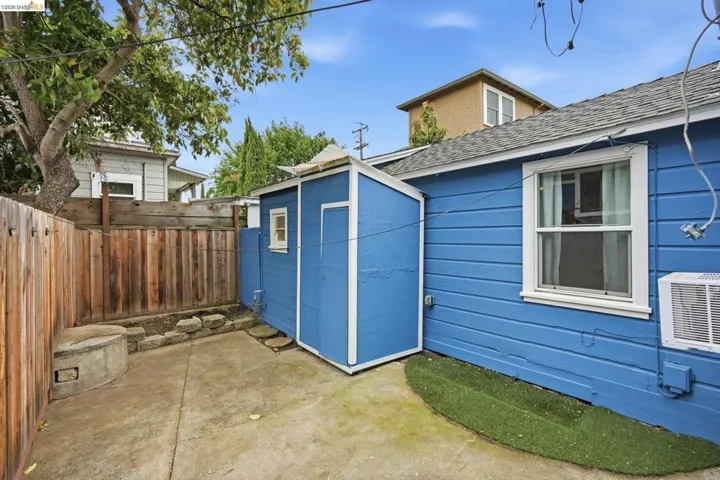 Concrete patio area featuring a wooden fence and a painted storage shed