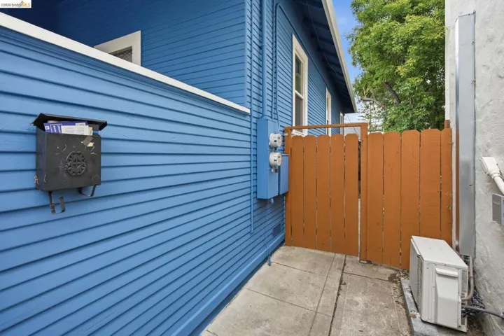 Exterior featuring blue horizontal siding, a wooden privacy gate, and a concrete walkway