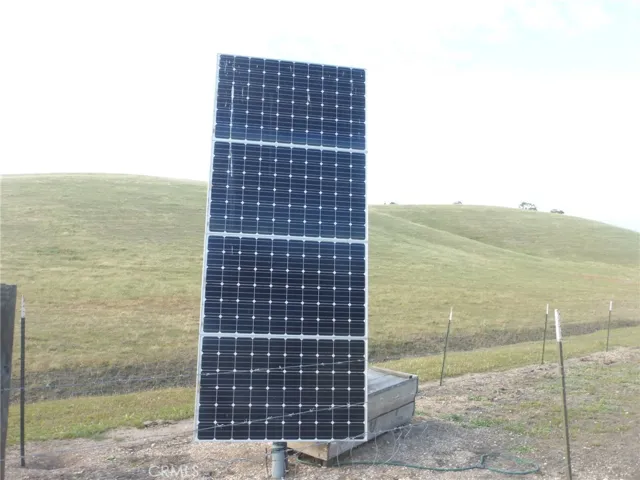 Well head with solar panels near metal shop building.