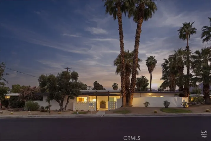 Mid-century modern home with clean lines, desert landscaping, and dramatic mountain sunset backdrop.
