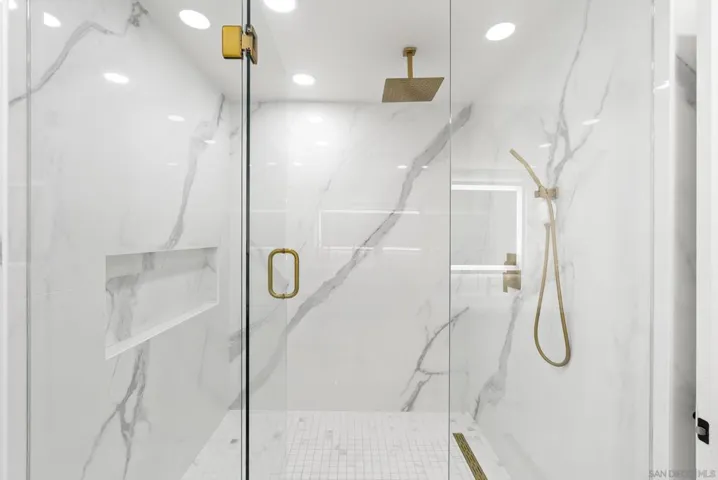 Wrapped in dramatic marble inspired stonework and warm brass finishes, this oversized walk in shower delivers a spa caliber experience with a clean, modern aesthetic and serene minimalist design.