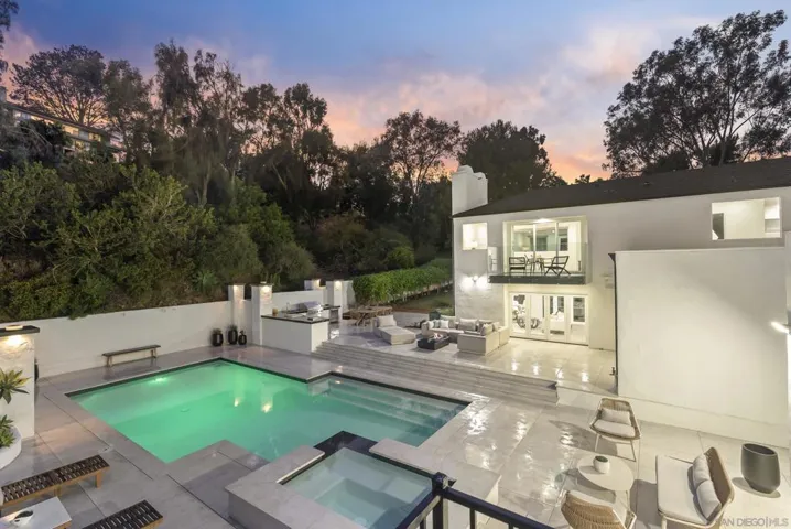 An elevated view over the resort-style pool and spa reveals the estate’s seamless indoor outdoor design, where expansive terraces, glowing sunset skies, and lush natural surroundings create a private retreat made for effortless entertaining.