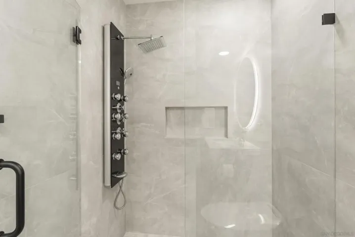 A sleek glass enclosed shower with soft stone finishes and a spa style body spray system, thoughtfully designed to deliver a refined and rejuvenating guest experience.