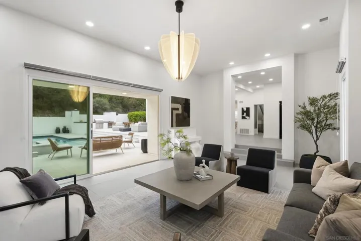 An elegant formal living room offering a quiet sense of sophistication, where expansive glass doors invite natural light and create a seamless connection to the resort-style outdoor living spaces.
