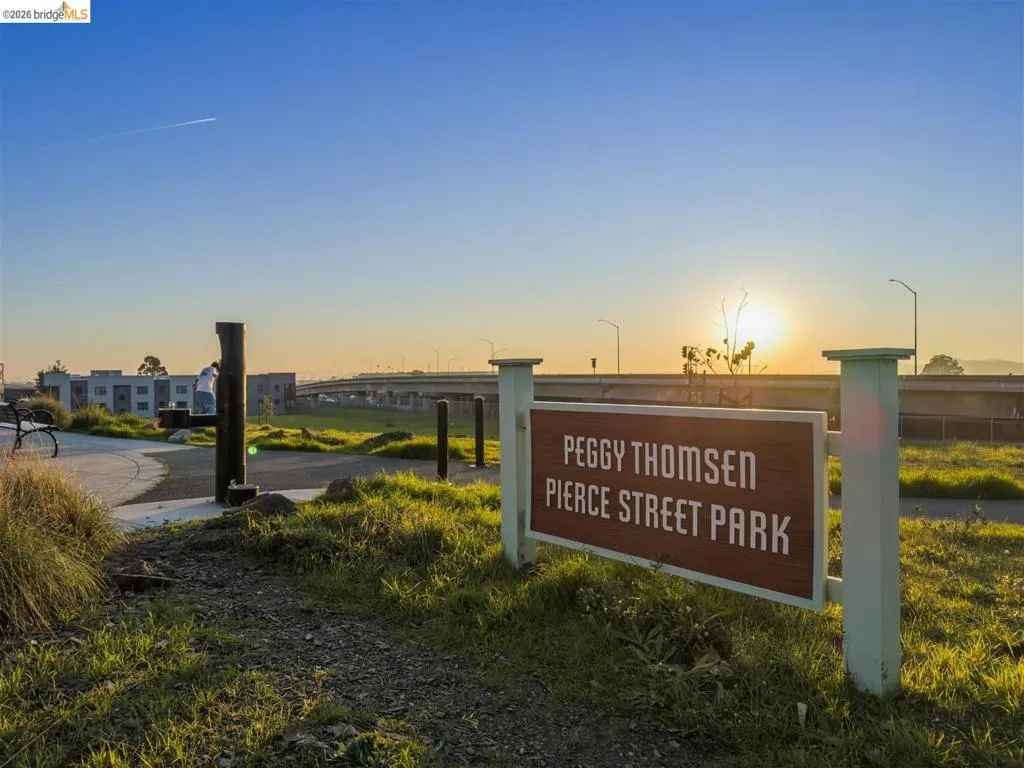 Park sign featuring "Peggy Thomsen Pierce Street Park" on a brown panel with white lettering