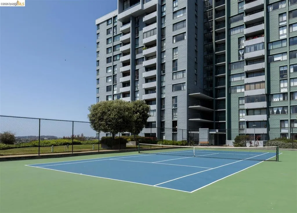 Regulation-size tennis court featuring a blue playing surface and green surrounding area