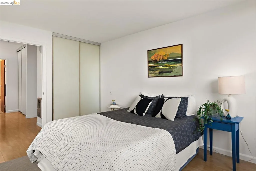 Bedroom featuring light wood-finish flooring, white walls, and a built-in sliding closet with frosted panels