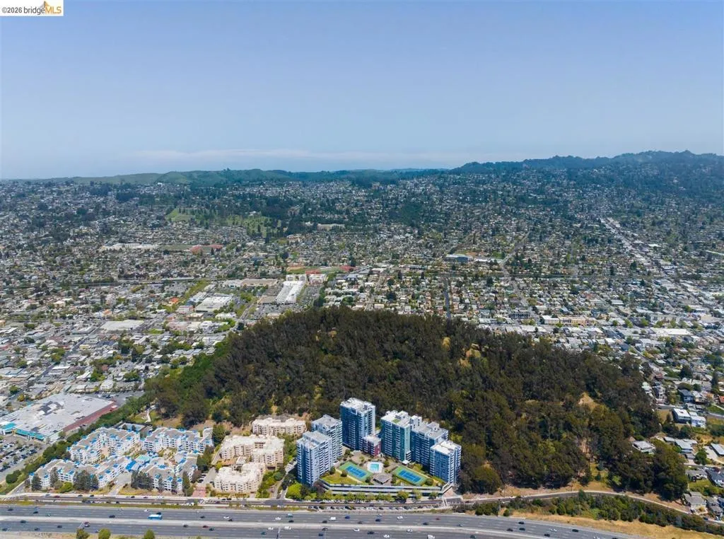 Aerial perspective showcasing multiple residential buildings surrounded by a dense tree-covered hill