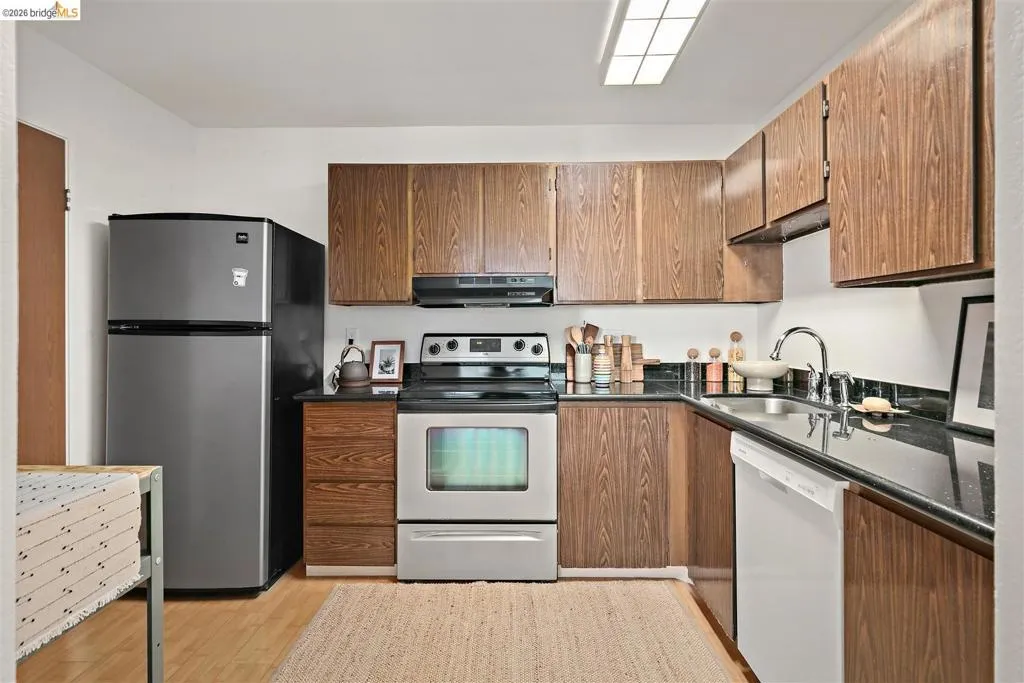 Kitchen featuring wood-finish cabinetry, black countertops, and stainless steel appliances