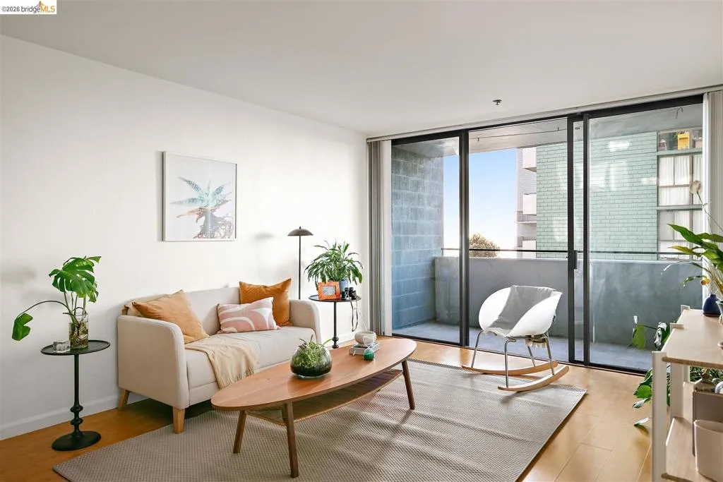 Living area featuring wood-finish flooring, light-toned walls, and abundant natural light from the expansive sliding glass doors