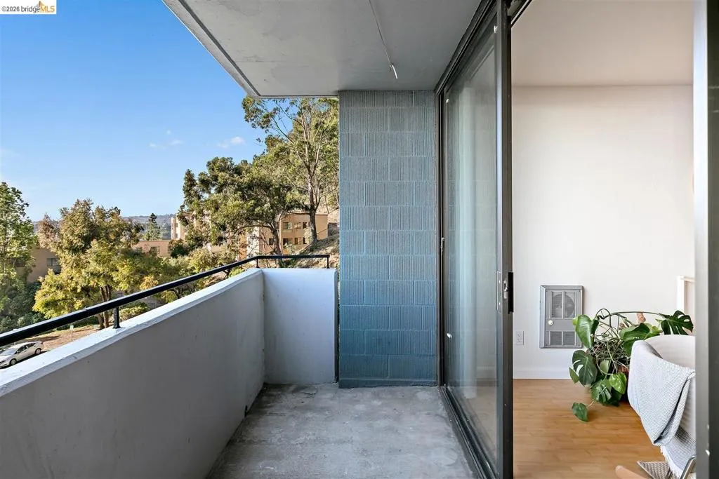 Private balcony featuring a concrete floor, dark metal railing, and a textured block wall