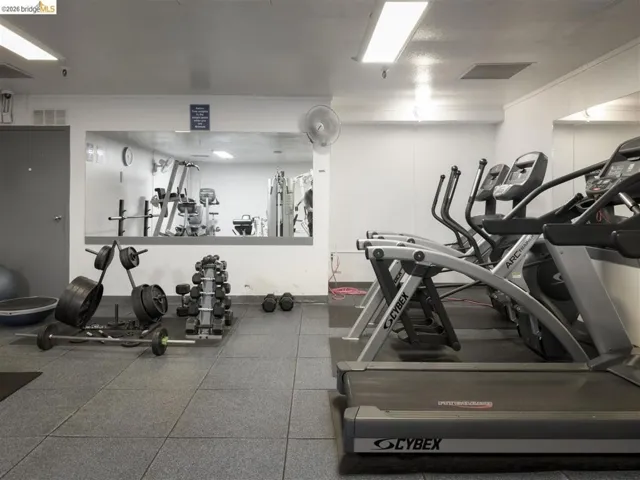 Fitness room featuring a mirrored wall, tiled flooring, fluorescent lighting, and a selection of cardio equipment