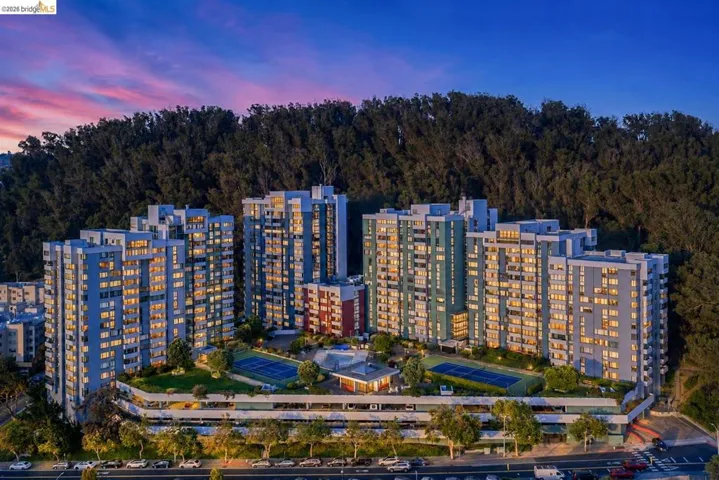 Expansive multi-building complex featuring multiple stories, numerous balconies, and a vibrant green rooftop