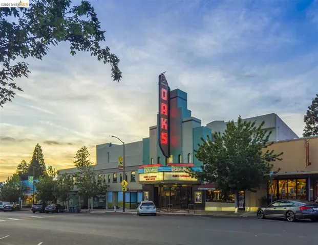 Art Deco facade featuring a prominent vertical marquee, multiple storefronts, a street-level entrance, and architectural lighting accents