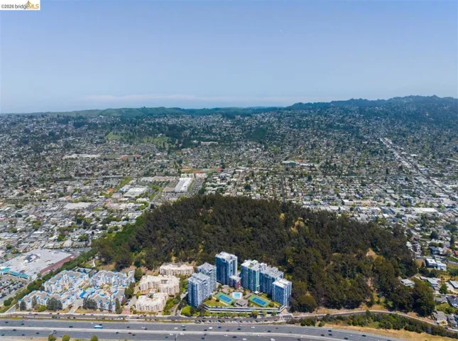 Aerial perspective showcasing multiple residential buildings surrounded by a dense tree-covered hill