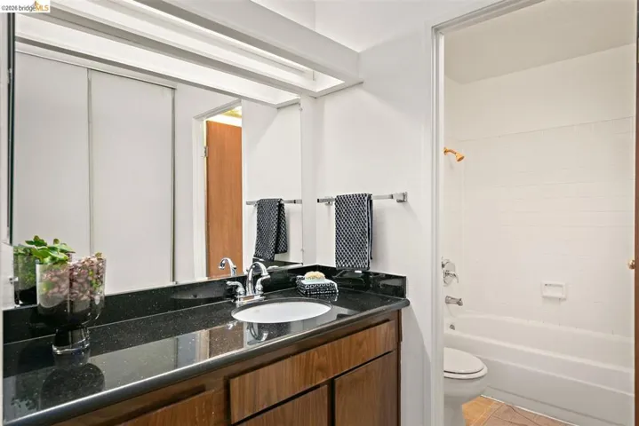 Bathroom vanity featuring a dark stone-finish countertop, undermount sink, and chrome faucet