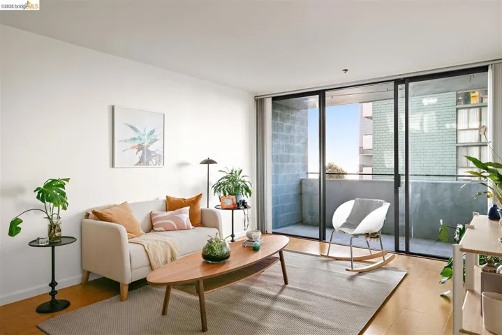 Living area featuring wood-finish flooring, light-toned walls, and abundant natural light from the expansive sliding glass doors