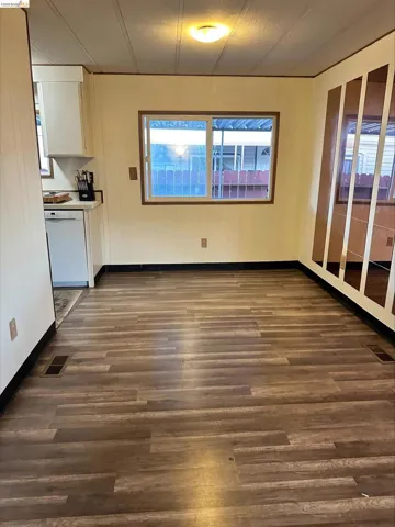 Unfurnished dining area featuring dark wood-style flooring and wooden walls