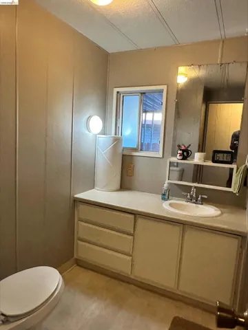 Half bath with vanity, a textured ceiling, and a decorative wall