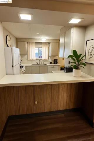 Kitchen featuring light countertops, white appliances, dark wood finished floors, and a peninsula