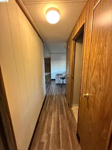 Hall featuring dark wood-style floors, wood walls, and a textured ceiling