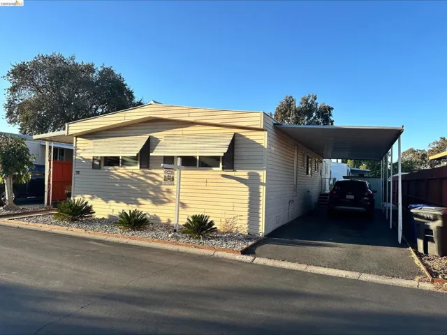 Manufactured / mobile home featuring a carport and asphalt driveway