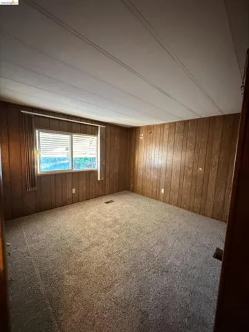 Carpeted spare room featuring wood walls