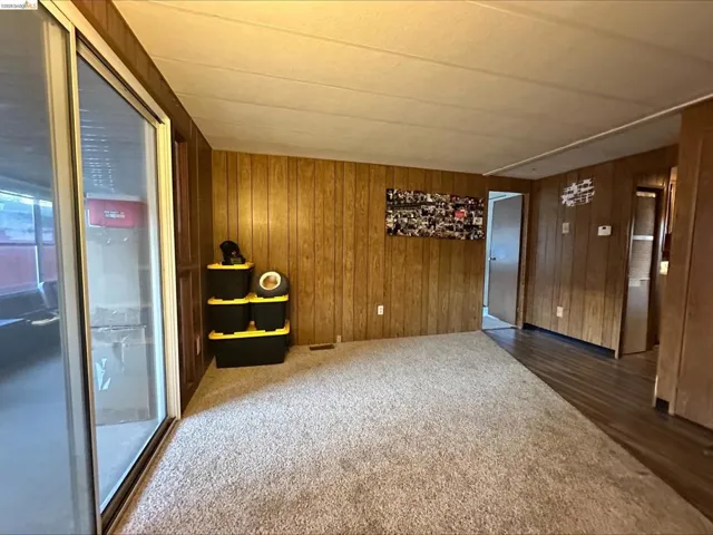 Unfurnished room with dark carpet and wood walls