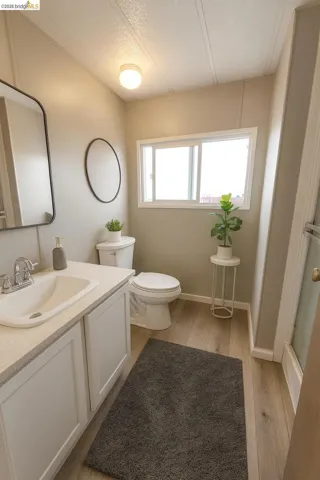 Full bath with vanity, light wood finished floors, a shower stall, and a textured ceiling