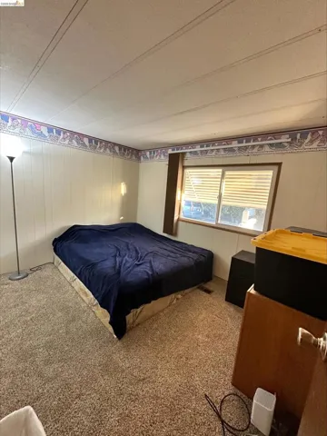 Carpeted bedroom with a textured ceiling and wooden walls