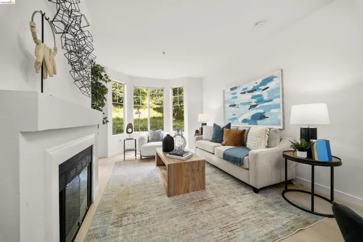 Living space featuring a white fireplace mantel, light wood-finish flooring, and a bay window with multiple panes