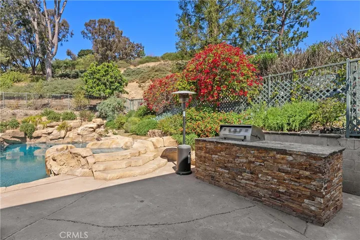 Outdoor kitchen/BBQ adjacent to pool on right side of yard.