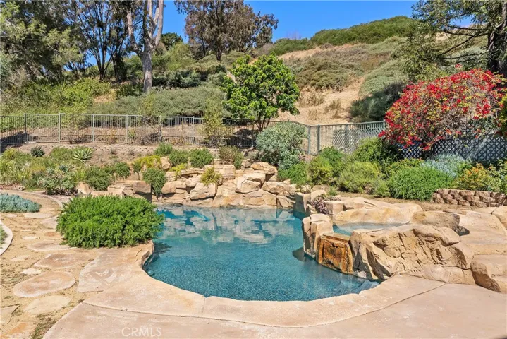 Private, sparkling, Pebbletec pool & spa with waterfall features in backyard.