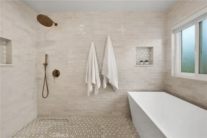 OVERSIZED SOAKING TUB, SHOWER HEAD AND WALL TO WALL STONE AND DESIGNERS TILES.