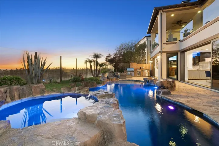 Resort style backyard with ample seating, sink, refrigerator, fire pit and BBQ island.
