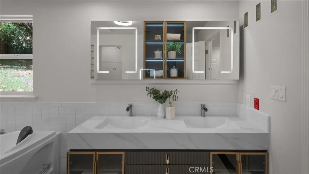 Primary bathroom features  floating vanity with dual sinks and lighted mirrors