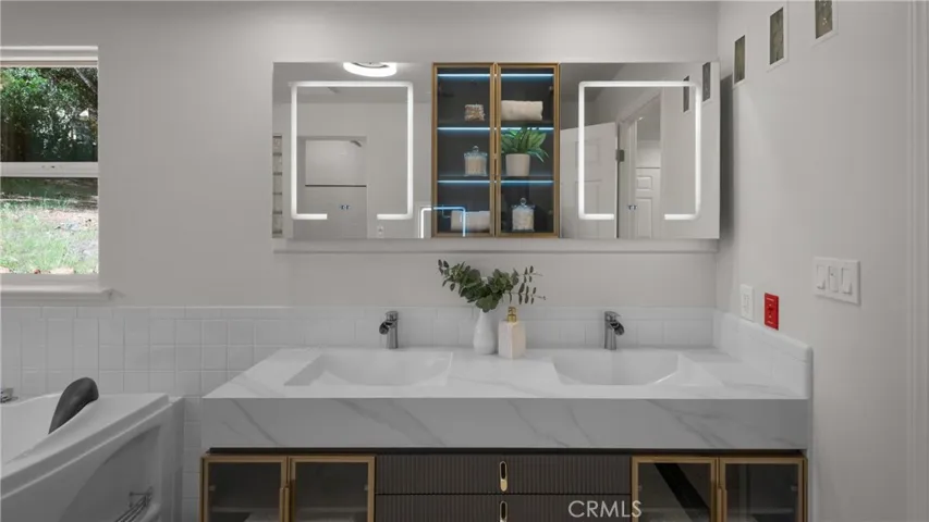 Primary bathroom features  floating vanity with dual sinks and lighted mirrors