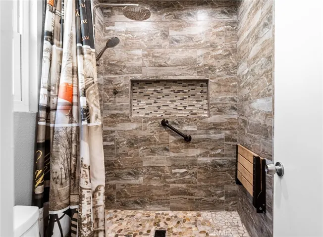 Beautifully updated walk-in shower with fold down bench and handle