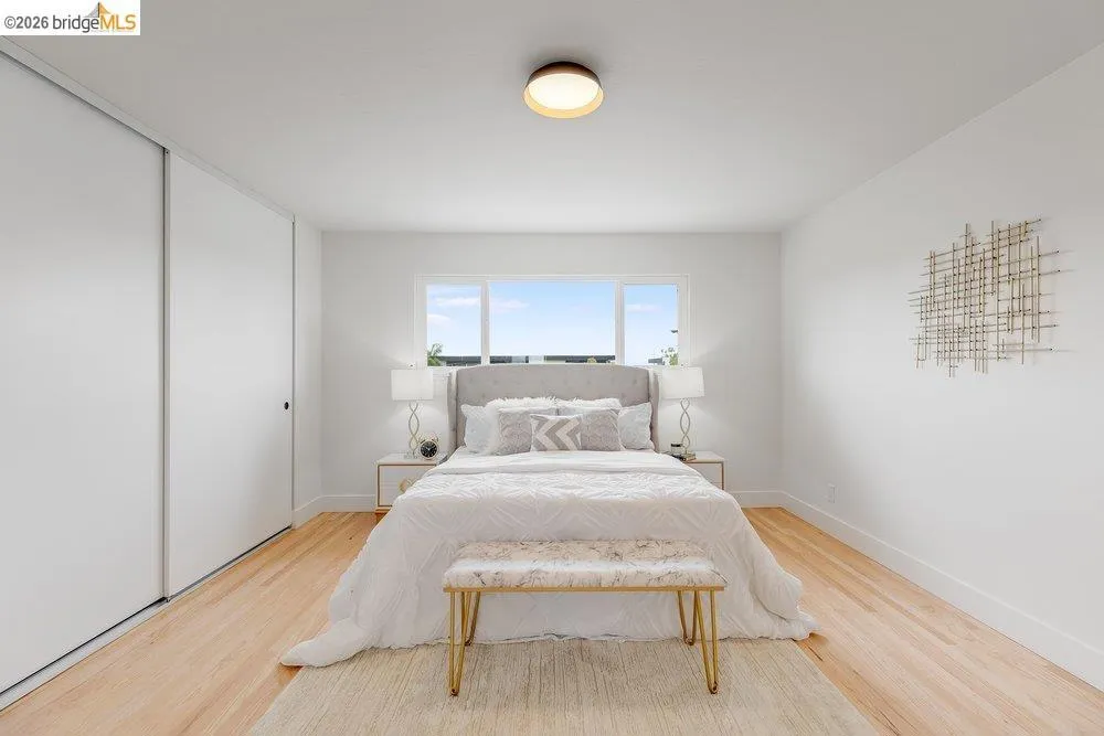 Light-filled room featuring a rectangular window, light wood-finish flooring, white walls, and a ceiling-mounted light fixture